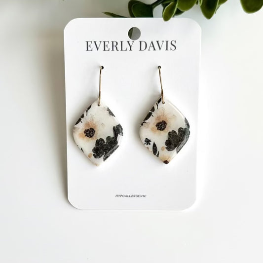 Everly Davis diamond-shaped clay earrings with a dark floral pattern on a white background.