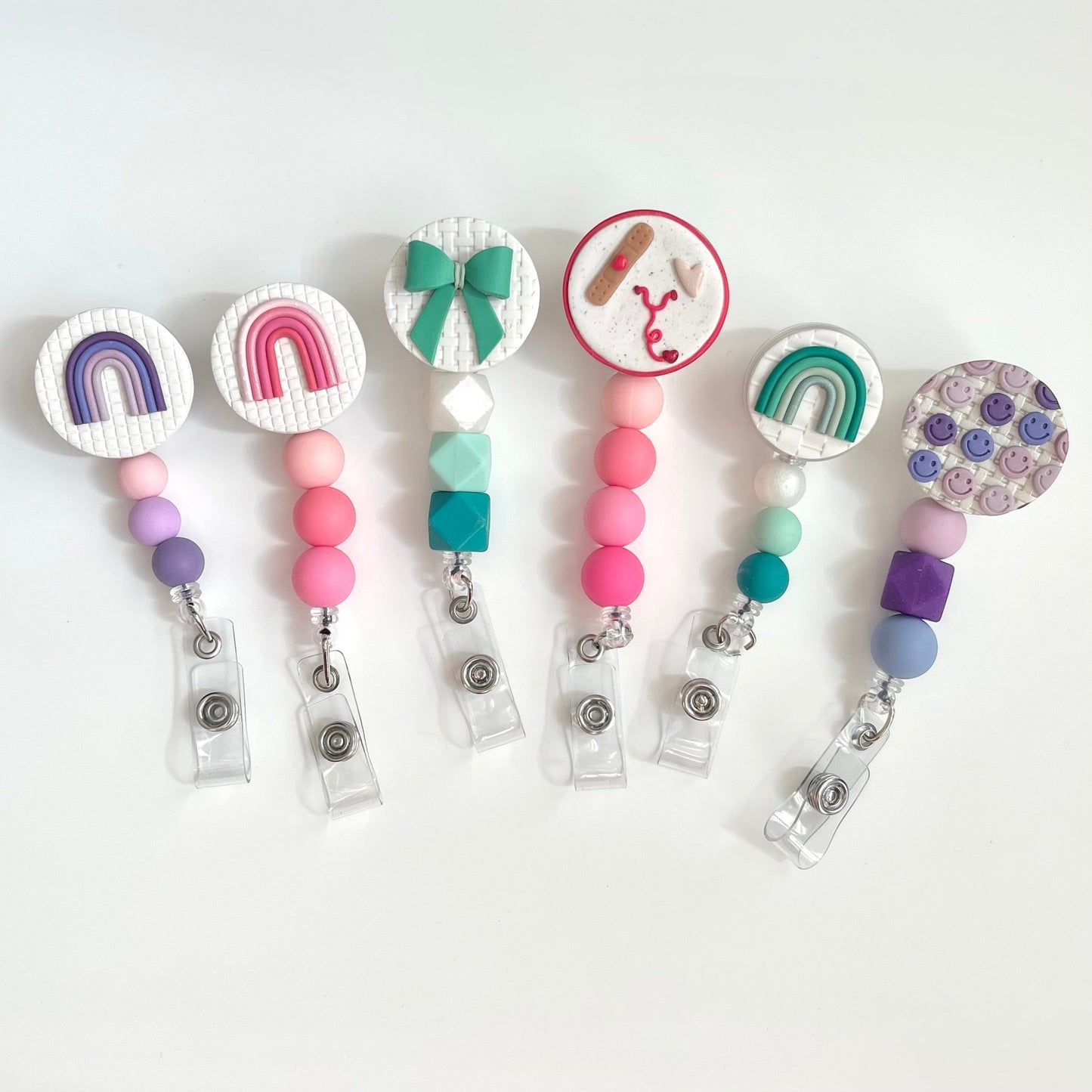 Everly Davis handmade beaded badge reels with rainbow, stethoscope, and smiley face charms. Silicone beads in pink, purple, teal, and blue.