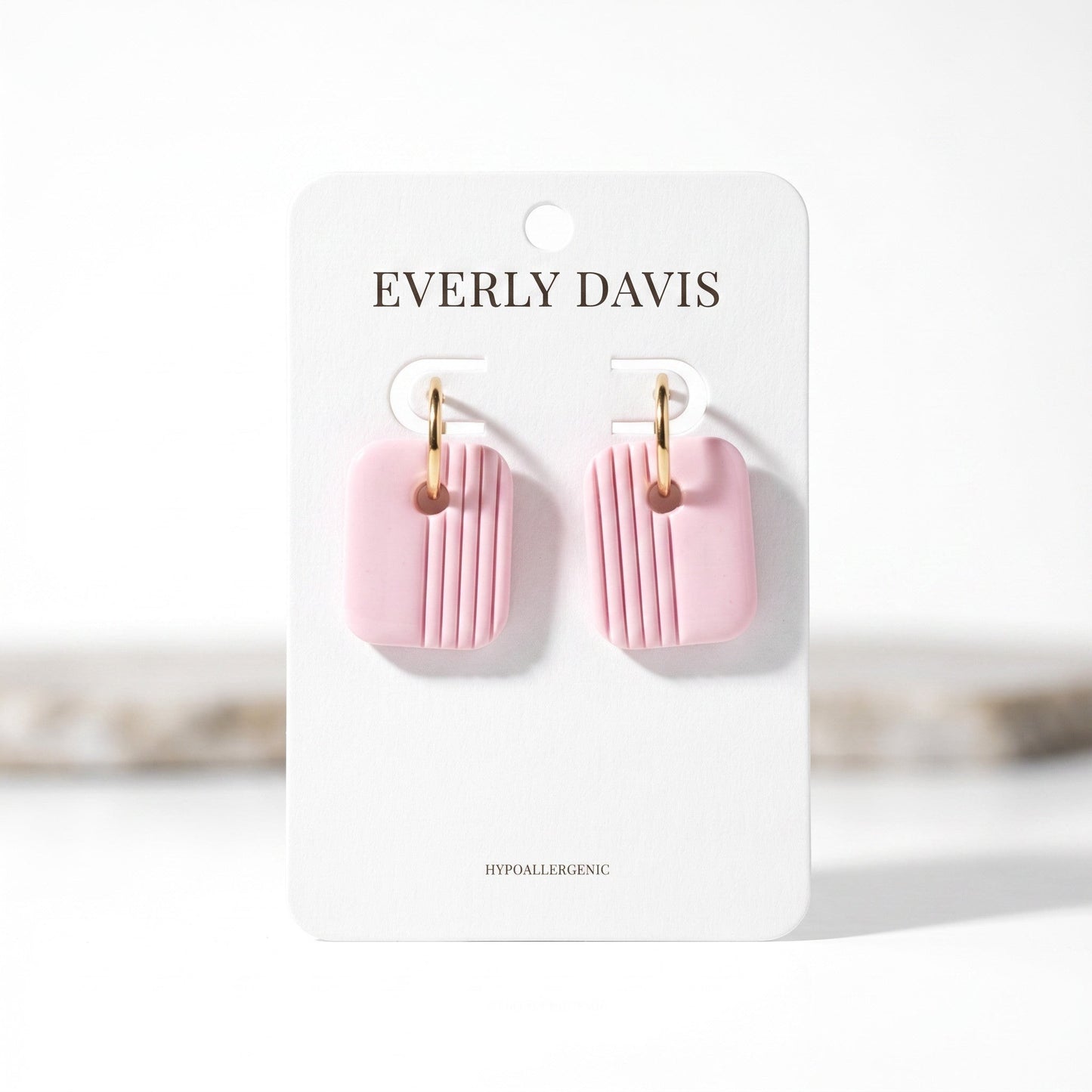 Everly Davis pink clay square earrings with vertical stripes and gold huggie hoops.