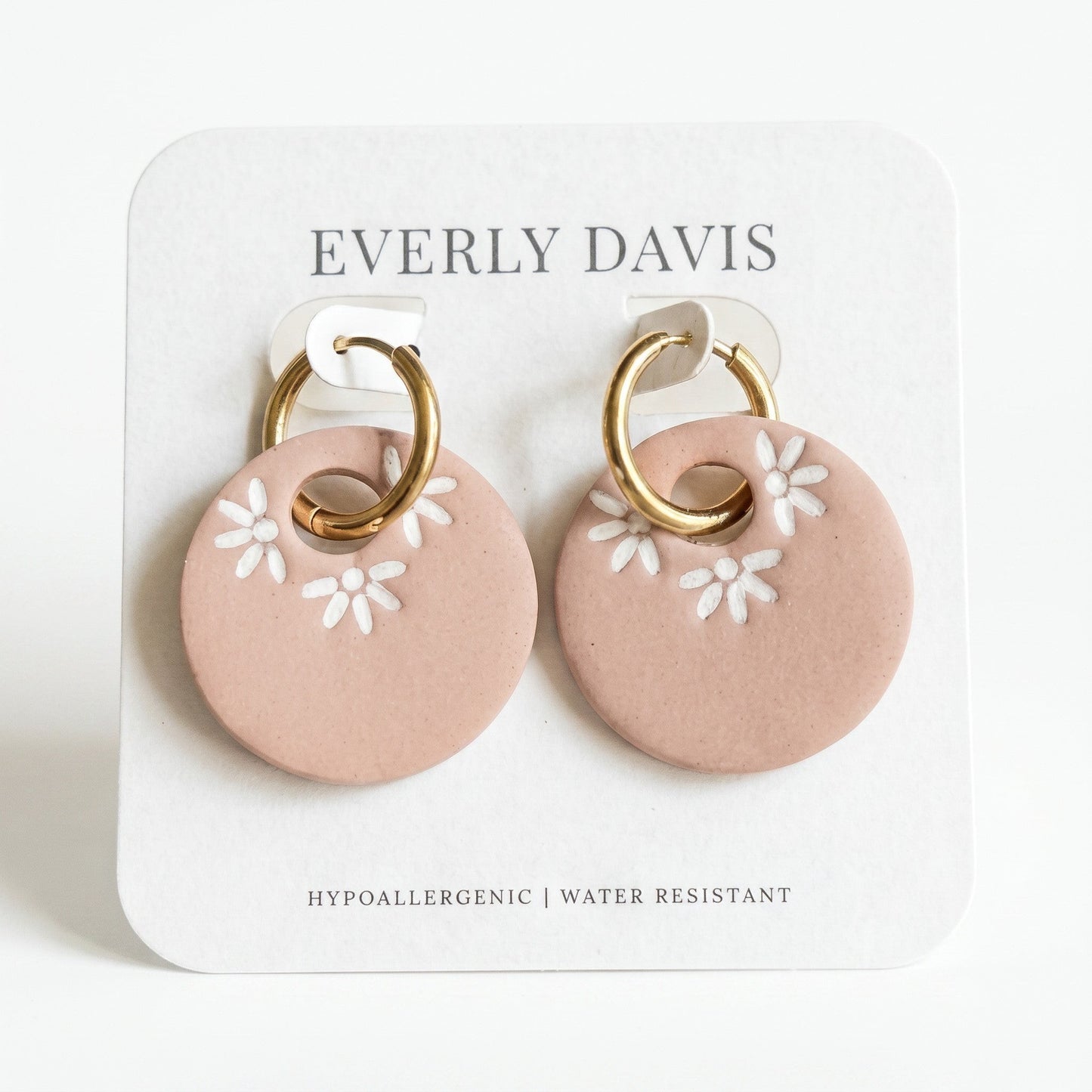 Everly Davis lightweight blush pink polymer clay hoop earrings with white daisy imprints and gold hardware.