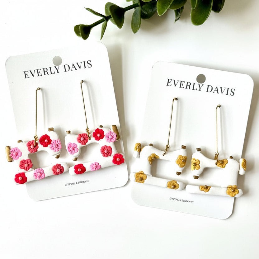 Everly Davis white dangle earrings shaped like sewing machines with pink, red, and yellow floral accents.