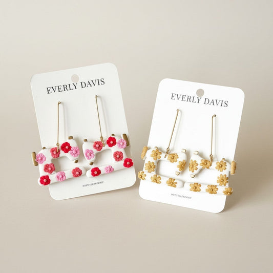 Everly Davis white dangle earrings shaped like sewing machines with pink, red, and yellow floral accents.