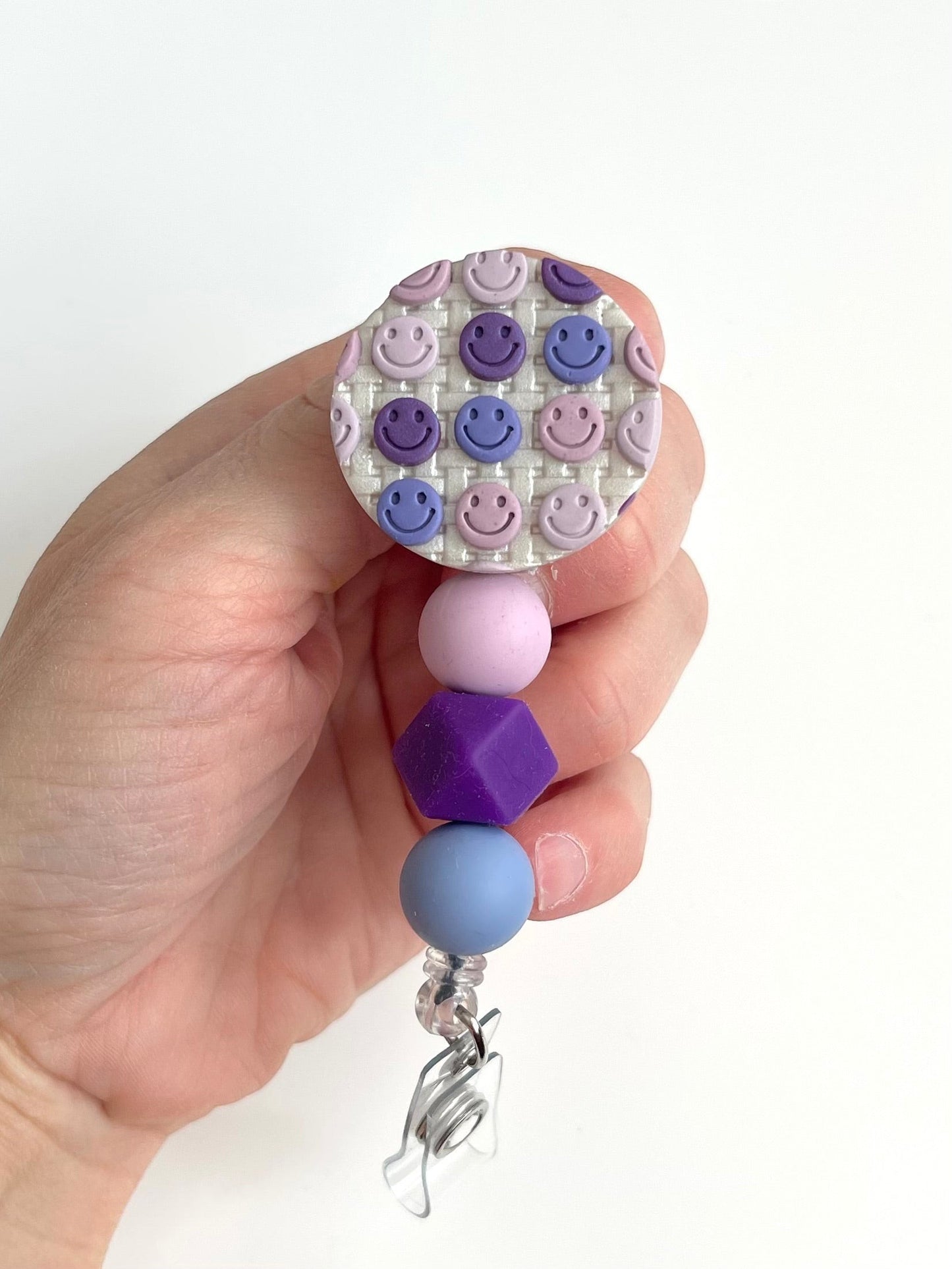 Everly Davis handmade beaded badge reel with purple and pink smiley faces and silicone beads in purple, pink, and blue.
