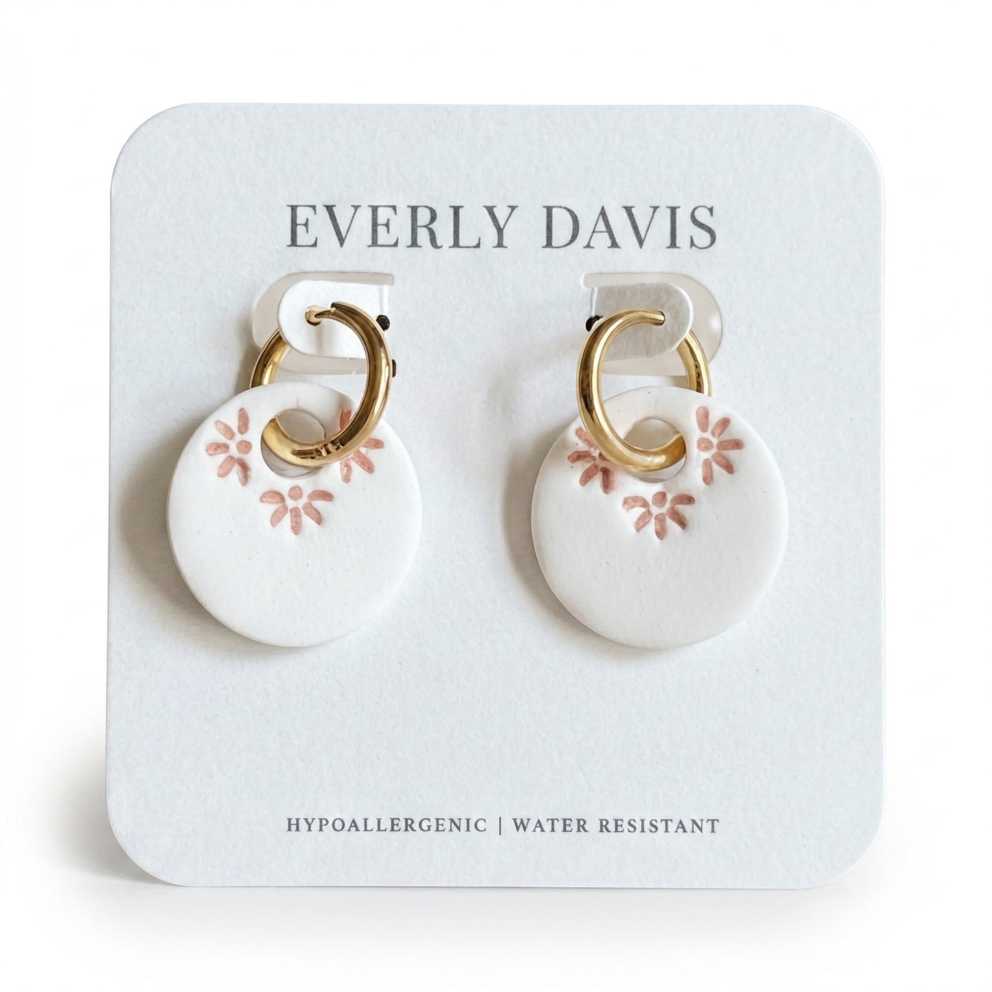 Everly Davis white polymer clay hoop earrings with gold-tone hoops and imprinted pink floral design. Hypoallergenic.