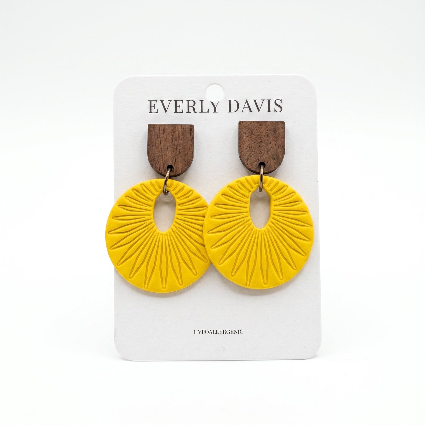 Everly Davis yellow circular drop earrings with dark wood studs and sunburst texture on a display card.